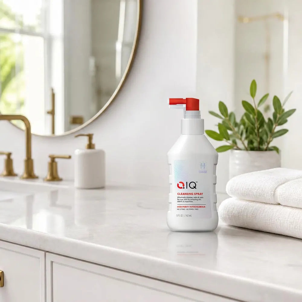 QIQ Skin Savior Cleansing Spray on a bright bathroom counter beside folded towels